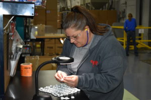 injection molding employee measuring parts.